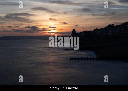 Sonnenuntergang und goldene Stunde am Hastings Pier, England, Großbritannien mit Blick auf Eastbourne mit dem Meer und den Groynes im Vordergrund.Promenade Stockfoto