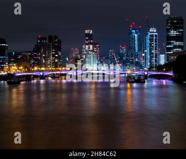 Ein Blick auf die Skyline von London, der die neuen Entwicklungen in Battersea und neun Ulmen in der Nacht von der Westminster-Brücke mit der themse zeigt Stockfoto