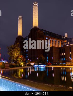 Eine Aufnahme des Battersea Power Station mit einem Teich im Vordergrund, aufgenommen in der Nacht, zeigt die Nordhöhe des Gebäudes. Stockfoto