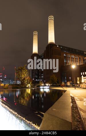 Eine Aufnahme des Battersea Power Station mit einem Teich im Vordergrund, aufgenommen in der Nacht, zeigt die Nordhöhe des Gebäudes. Stockfoto