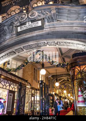 Burlington Arcade Weihnachten traditionelle luxuriöse Londoner Einkaufspassage belebte Einfahrt in Piccadilly mit Weihnachtslichtern, Girlanden und Dekorationen in der Dämmerung. Viktorianische Einkaufspassage mit traditionellem Einkaufserlebnis. Stockfoto