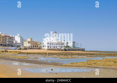 Angeln Korrale bei Ebbe am Strand mit dem Leuchtturm Chipiona im Hintergrund, Cádiz, Andalusien, Spanien. Andalusische Dorftradition Stockfoto