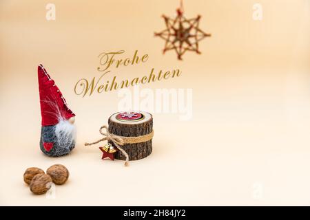 Weihnachtspostkarte mit Text Frohe Weihnachten und beigem Hintergrund, Nüssen, Holzkerze und einem lustigen Gnom Stockfoto