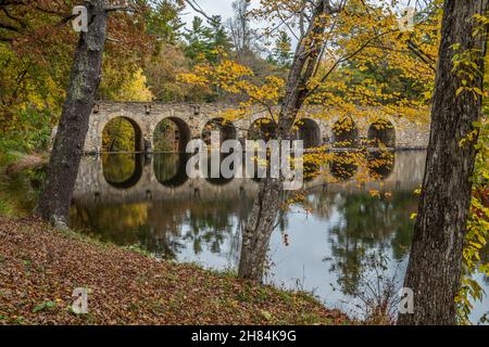 Die sieben Bögen Brücke, die über Byrd See im Cumberland Mountain State Park, umgeben von den lebendigen bunten Bäumen des Herbstes ein Spiegel re kreuzt Stockfoto