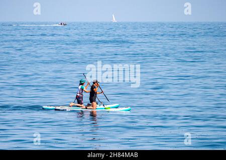 Paddelboarder auf einem ruhigen Meer vor Megavissey, Cornwall, Großbritannien. Stockfoto