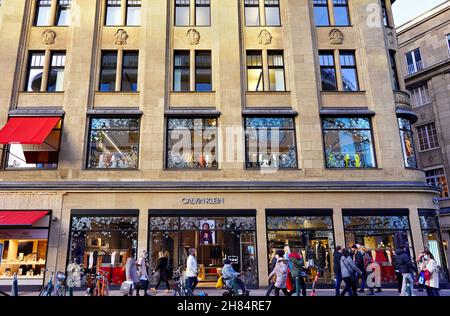 Das Hohenzollernhaus mit dem Calvin Klein Store auf der Einkaufsmeile Schadowstraße in Düsseldorf/Deutschland, während der Weihnachtszeit mit geschäftigen Einkäufern. Stockfoto