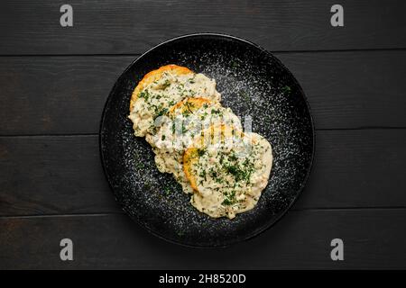 Draufsicht auf Kartoffelpatty mit frittiertem Boletus und cremiger Sauce auf einem Teller Stockfoto