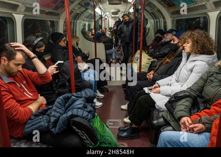 London, Großbritannien. 27. November 2021. Menschen, die auf der Bakerloo-Linie unterwegs sind, wie der Premierminister Boris Johnson auf einer Pressekonferenz bekannt gab, die Maßnahmen zur Eindämmung der Ausbreitung des Coronavirus in Großbritannien als Reaktion auf zwei Fälle der Omicron-Variante, die im Land entdeckt werden, ankündigte. Zu den neuen Maßnahmen gehören das obligatorische Tragen von Gesichtsmasken in Geschäften und öffentlichen Verkehrsmitteln sowie PCR-Tests für Reisende, die nach Großbritannien einreisen. Kredit: Stephen Chung / Alamy Live Nachrichten Stockfoto