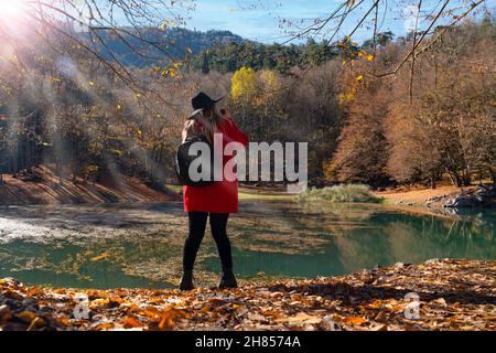 Rückansicht einer Fotografin in roter Jacke und schwarzem Hut, die Fotos in Sevenlakes (yedigoller), Bolu, Türkei, macht Stockfoto