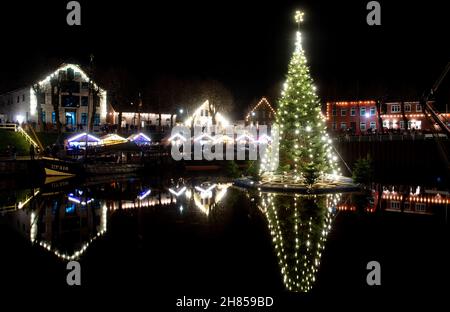 Carolinensiel, Deutschland. 27th. November 2021. Der schwimmende Weihnachtsbaum leuchtet im historischen Hafen des Dorfes. Seit 1995 wird der Baum traditionell am Samstag vor dem ersten Adventssonntag aufgesetzt und die Lichter eingeschaltet. Quelle: Hauke-Christian Dittrich/dpa/Alamy Live News Stockfoto