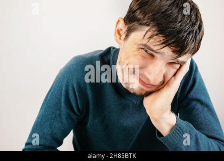 Nahaufnahme. Lächelnder junger Mann, der an seinem Schreibtisch sitzt. Menschen, Emotionen. Stockfoto