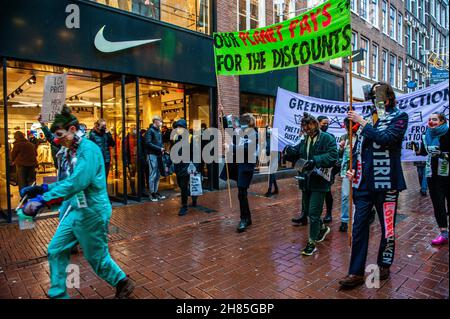 Amsterdam, Niederlande. 27th. November 2021. XR-Aktivisten halten während der Demonstration Transparente.Extinction Rebellion organisierte im Zentrum von Amsterdam eine Modeparade, um die schnelle Mode zu verspotten und die Aufmerksamkeit auf die ausbeuterischen, profitorientierten und grünlichen Praktiken der Fast Fashion-Industrie zu lenken. Die Klimaaktivisten marschierten durch die Haupteinkaufsstraßen, tanzten und trugen reparierte und gebrauchte Kleidung. Kredit: SOPA Images Limited/Alamy Live Nachrichten Stockfoto