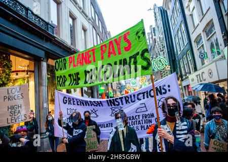 Amsterdam, Niederlande. 27th. November 2021. XR-Aktivisten halten während der Demonstration Transparente.Extinction Rebellion organisierte im Zentrum von Amsterdam eine Modeparade, um die schnelle Mode zu verspotten und die Aufmerksamkeit auf die ausbeuterischen, profitorientierten und grünlichen Praktiken der Fast Fashion-Industrie zu lenken. Die Klimaaktivisten marschierten durch die Haupteinkaufsstraßen, tanzten und trugen reparierte und gebrauchte Kleidung. Kredit: SOPA Images Limited/Alamy Live Nachrichten Stockfoto