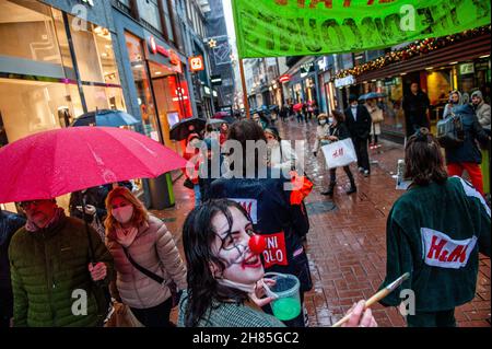 Amsterdam, Niederlande. 27th. November 2021. Ein XR-Aktivist, der als Clown gekleidet war, wurde während der Demonstration gesehen.Extinction Rebellion organisierte im Zentrum von Amsterdam eine Modeparade, um die schnelle Mode zu verspotten und die Aufmerksamkeit auf die ausbeuterischen, profitorientierten und grünlichen Praktiken der Fast-Fashion-Branche zu lenken. Die Klimaaktivisten marschierten durch die Haupteinkaufsstraßen, tanzten und trugen reparierte und gebrauchte Kleidung. Kredit: SOPA Images Limited/Alamy Live Nachrichten Stockfoto