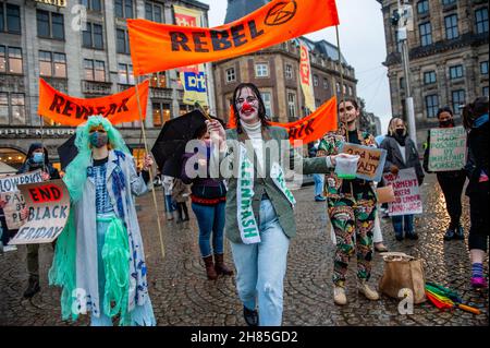 Amsterdam, Niederlande. 27th. November 2021. Ein XR-Aktivist, der als Clown gekleidet war, wurde während der Demonstration gesehen.Extinction Rebellion organisierte im Zentrum von Amsterdam eine Modeparade, um die schnelle Mode zu verspotten und die Aufmerksamkeit auf die ausbeuterischen, profitorientierten und grünlichen Praktiken der Fast-Fashion-Branche zu lenken. Die Klimaaktivisten marschierten durch die Haupteinkaufsstraßen, tanzten und trugen reparierte und gebrauchte Kleidung. Kredit: SOPA Images Limited/Alamy Live Nachrichten Stockfoto