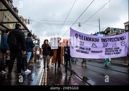 Amsterdam, Niederlande. 27th. November 2021. XR-Aktivisten halten während der Demonstration ein Banner.Extinction Rebellion organisierte im Zentrum von Amsterdam eine Modeparade, um die schnelle Mode zu verspotten und die Aufmerksamkeit auf die ausbeuterischen, profitorientierten und grünlichen Praktiken der Fast Fashion-Industrie zu lenken. Die Klimaaktivisten marschierten durch die Haupteinkaufsstraßen, tanzten und trugen reparierte und gebrauchte Kleidung. Kredit: SOPA Images Limited/Alamy Live Nachrichten Stockfoto