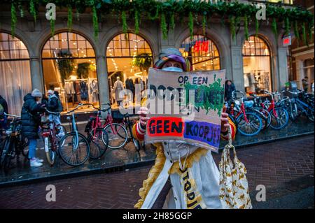 Amsterdam, Niederlande. 27th. November 2021. Während der Demonstration wird ein XR-Aktivist mit einem Plakat gesehen.Extinction Rebellion organisierte im Zentrum von Amsterdam eine Modeparade, um die schnelle Mode zu verspotten und die Aufmerksamkeit auf die ausbeuterischen, profitorientierten und grünwaschenden Praktiken der schnellen Modeindustrie zu lenken. Die Klimaaktivisten marschierten durch die Haupteinkaufsstraßen, tanzten und trugen reparierte und gebrauchte Kleidung. Kredit: SOPA Images Limited/Alamy Live Nachrichten Stockfoto