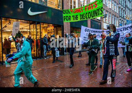 Amsterdam, Niederlande. 27th. November 2021. XR-Aktivisten halten während der Demonstration Transparente.Extinction Rebellion organisierte im Zentrum von Amsterdam eine Modeparade, um die schnelle Mode zu verspotten und die Aufmerksamkeit auf die ausbeuterischen, profitorientierten und grünlichen Praktiken der Fast Fashion-Industrie zu lenken. Die Klimaaktivisten marschierten durch die Haupteinkaufsstraßen, tanzten und trugen reparierte und gebrauchte Kleidung. (Foto: Ana Fernandez/SOPA Images/Sipa USA) Quelle: SIPA USA/Alamy Live News Stockfoto