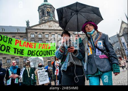 Amsterdam, Niederlande. 27th. November 2021. Ein XR-Aktivist spricht während der Demonstration.Extinction Rebellion organisierte im Zentrum von Amsterdam eine Modeparade, um die schnelle Mode zu verspotten und die Aufmerksamkeit auf die ausbeuterischen, profitorientierten und grünlichen Praktiken der schnellen Modeindustrie zu lenken. Die Klimaaktivisten marschierten durch die Haupteinkaufsstraßen, tanzten und trugen reparierte und gebrauchte Kleidung. (Foto: Ana Fernandez/SOPA Images/Sipa USA) Quelle: SIPA USA/Alamy Live News Stockfoto