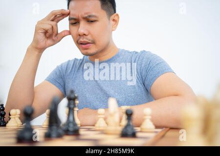Junger Mann mit Händen auf dem Kopf, während er Schach spielt Stockfoto