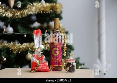 Luomu Rose Glögi - ein traditionelles organisch-alkoholisches finnisches Glogg-Getränk mit Lindt-Schokolade, Rosinen und Mandeln auf einem Tisch mit einem Weihnachtsbaum. Stockfoto