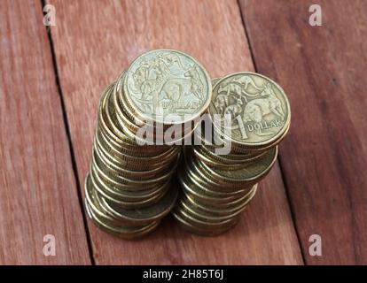 Zwei Stapel australischer 1-Dollar-Münzen auf einem Holzhintergrund. Geringe Schärfentiefe. Stockfoto