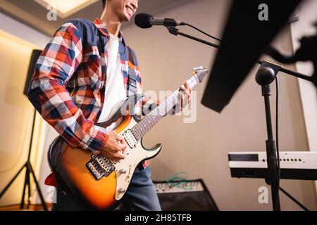 Ein männlicher Gitarrist spielt bei der Probe mit seiner Band eine E-Gitarre Stockfoto