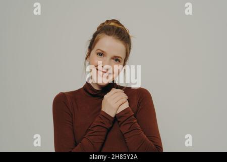 Dankbare, dankbare junge Frau, die gefaltete Hände auf der Brust hält und Dankbarkeit und Dankbarkeit zum Ausdruck bringt Stockfoto