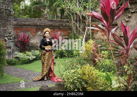 Frau in einem gewobenen Sarong in einem traditionellen balinesischen Garten Stockfoto