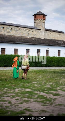 Ein Mann und ein Mädchen in mittelalterlichen Kleidern auf dem Gebiet der Burg Stockfoto