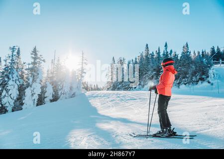 Alpine Abfahrt. Skimorträt einer alpinen Skifahrerin mit Skiern, Helm, cooler Skibrille und Hardshell-Winterjacke und Skihandschuhen bei Kälte Stockfoto