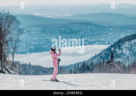 Frau, die mit dem Telefon im Skiurlaub fotografiert - Frau, die mit der Telefon-App auf der Skipiste unterwegs ist und Fotos von der erstaunlichen Winterlandschaft macht Stockfoto