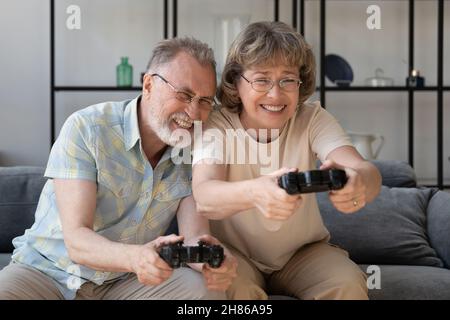 Ältere Gamer halten Videospiel-Controller, Konsole, genießen virtuelle Schlacht Stockfoto
