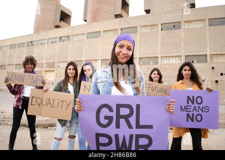 Lächelnde Feministin mit Spruchbändern gegen einen Protest. Viel Spaß bei der Vorführung. Stockfoto