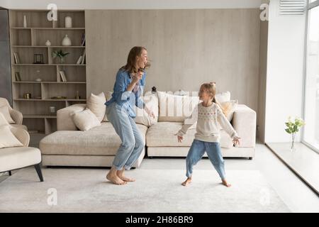 Glückliche junge Mutter, die mit kleinen Töchtern tanzt. Stockfoto