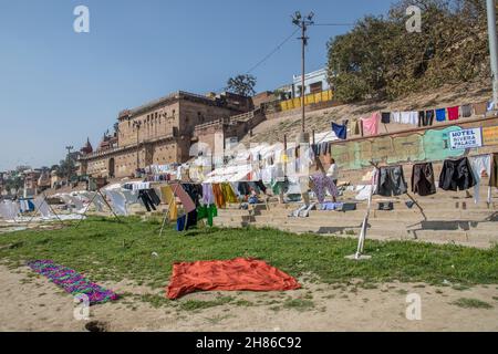 Wäscheservice Tag auf dem Ganges, Varanasi, Uttar Pradesh, Indien. Kleidung und Bettwäsche sind im Fluss und verteilen sich auf die Bank des Flusses zu trocknen Waschen Stockfoto