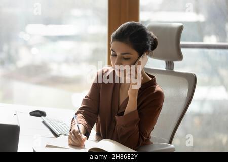 Konzentrierte junge indische Frau, die in einem modernen Büro arbeitet. Stockfoto