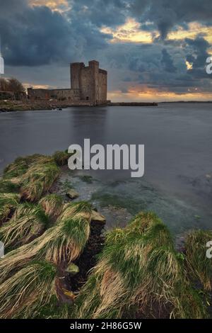 Dramatische, wolkige Sonnenuntergangsszenerie von Oranmore Castle an der felsigen Küste des Wild atlantic Way in der Grafschaft Galway, Irland Stockfoto