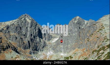 Eine rote Seilbahn auf dem Weg von Skalnate pleso zum Lomnitzer Gipfel. Die rote Gondel fährt auf den Lomnica-Gipfel in der Hohen Tatra. Slowakei. Stockfoto