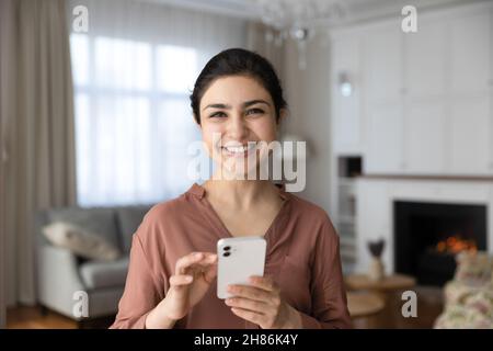 Porträt einer lächelnden indischen Frau, die das Smartphone in den Händen hält. Stockfoto