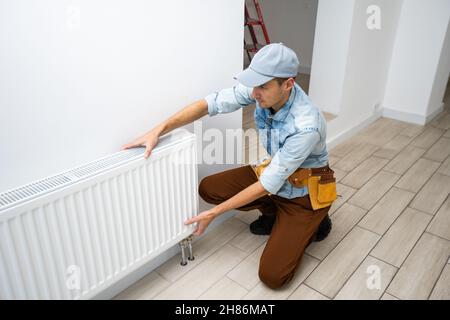 Ein Mann wechselt die Heizung im Haus, Heizkörper. Das Konzept der modernen Heizung, Ersatz der alten durch eine neue. Wärme im Haus Stockfoto