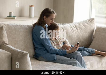 Glückliche junge Mutter und kleines Kind mit Handy. Stockfoto