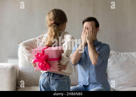 Rückansicht glücklich kleines Kind hält verpackt Box hinter dem Rücken. Stockfoto