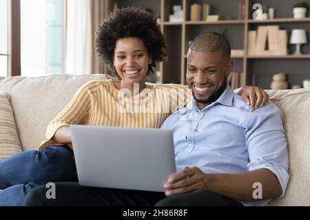 Glückliches positives junges gemischtes Rennpaar, das Videoanruf macht Stockfoto