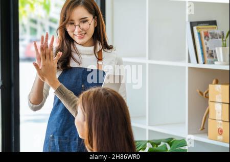 Verkaufen Sie Produkte an Unternehmer online. Konzentrieren Sie sich auf das Gesicht einer Frau in Weiß, die einer Freundin, deren Online-Verkäufe ihre übertrafen, Freude macht Stockfoto