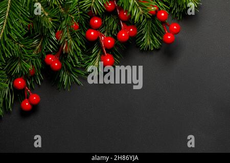 Weihnachten Grenze mit frischen Tannenzweigen und roten Beeren auf schwarzem Papier Hintergrund angeordnet, kopieren Platz für Text Stockfoto