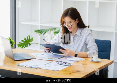 Arbeiten Sie von zu Hause aus. Gründen Sie einen Inhaber eines kleinen Unternehmens, indem Sie Stifte und Dokumente, persönliche Geschäftseinnahmen und Computer zur Arbeit verwenden. Stockfoto