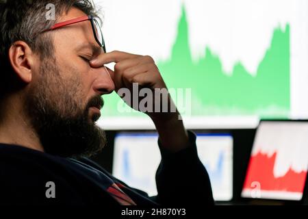 Deprimierter Geschäftsmann vor dem Computer mit Diagramm des erfolglosen Geschäfts auf dem Bildschirm. Hochwertige Fotos. Stockfoto
