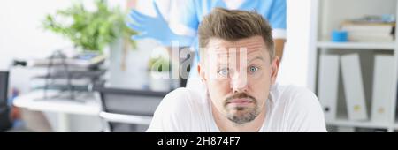 Junger trauriger Mann, der auf der Couch vor dem Proktologen in der Klinik liegt Stockfoto