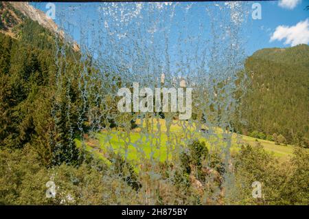 Tiroler Alpenlandschaft wie durch einen Vorhang aus Wasser hinter einem Wasserfall gesehen. Im Stubaital, Tirol, Österreich fotografiert. Stockfoto